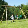 Scène d’ambiance dans un jardin avec un enfant sur la balancelle et une balançoire simple du portique en bois Julie 4 agrès